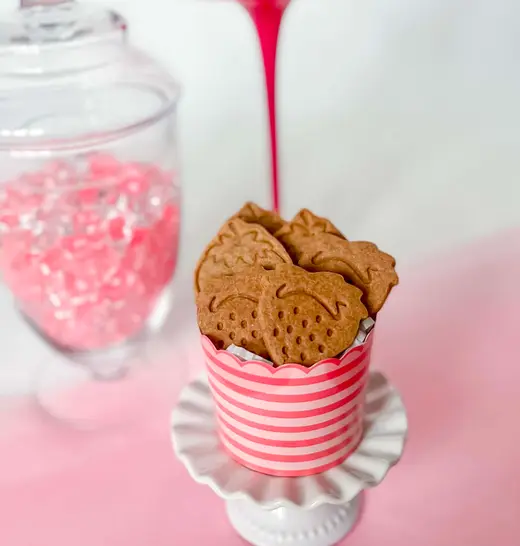 Strawberry-shaped cookies in a pink striped cup on a mini cake stand